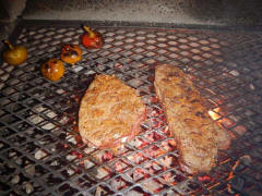 steaks cooking on precast outdoor fireplace